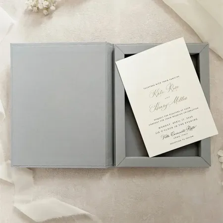 Grey wedding invitation box opened beside the card